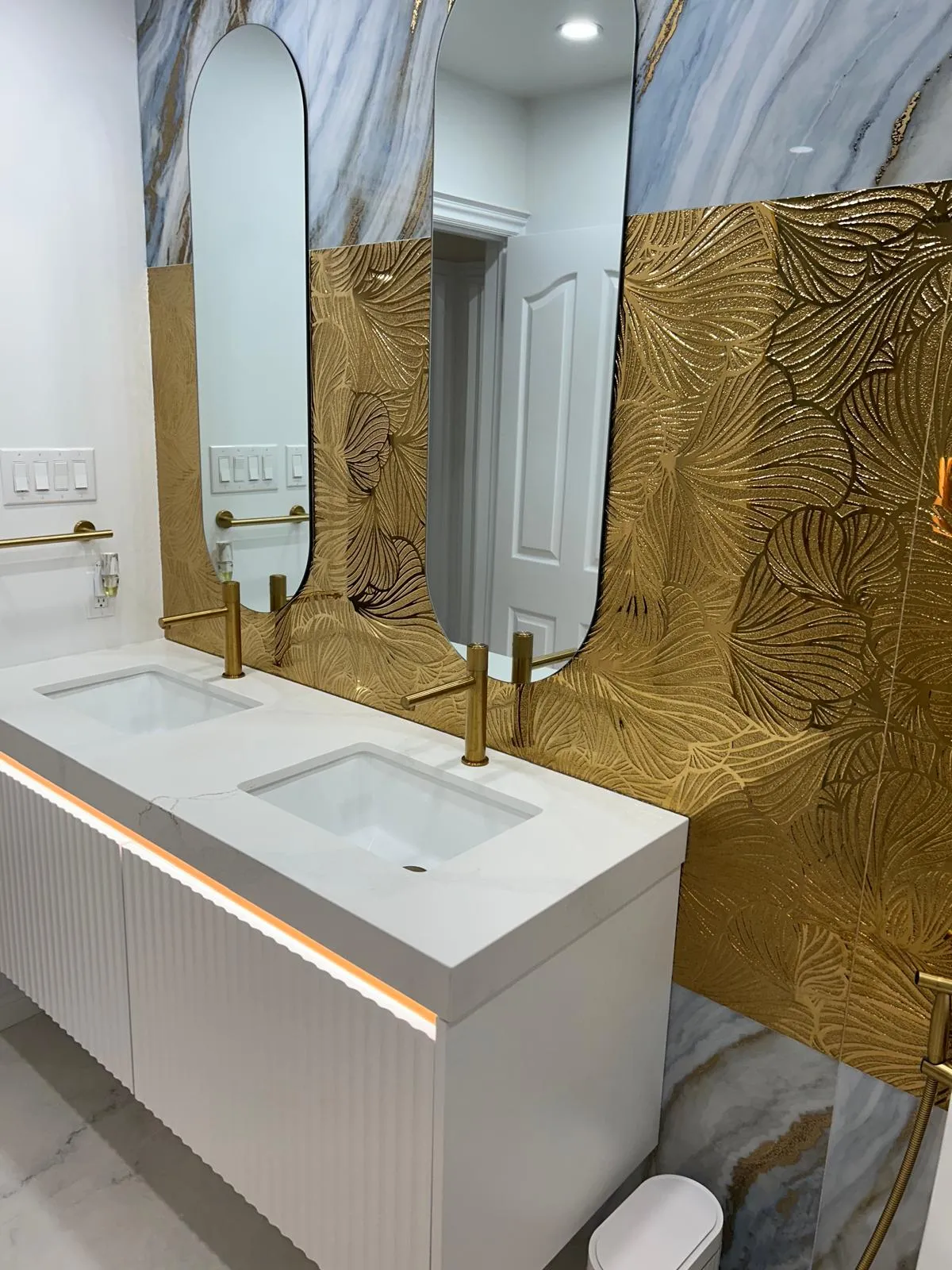 Freestanding double-sided feature wall in black and gold marble-effect porcelain with a linear electric fireplace