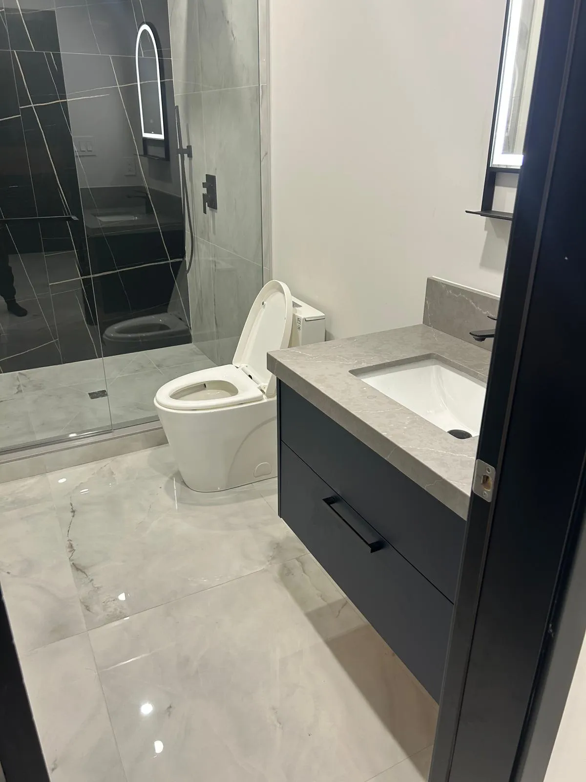 Frameless glass shower enclosure in large-format marble-effect porcelain with brass shower fittings